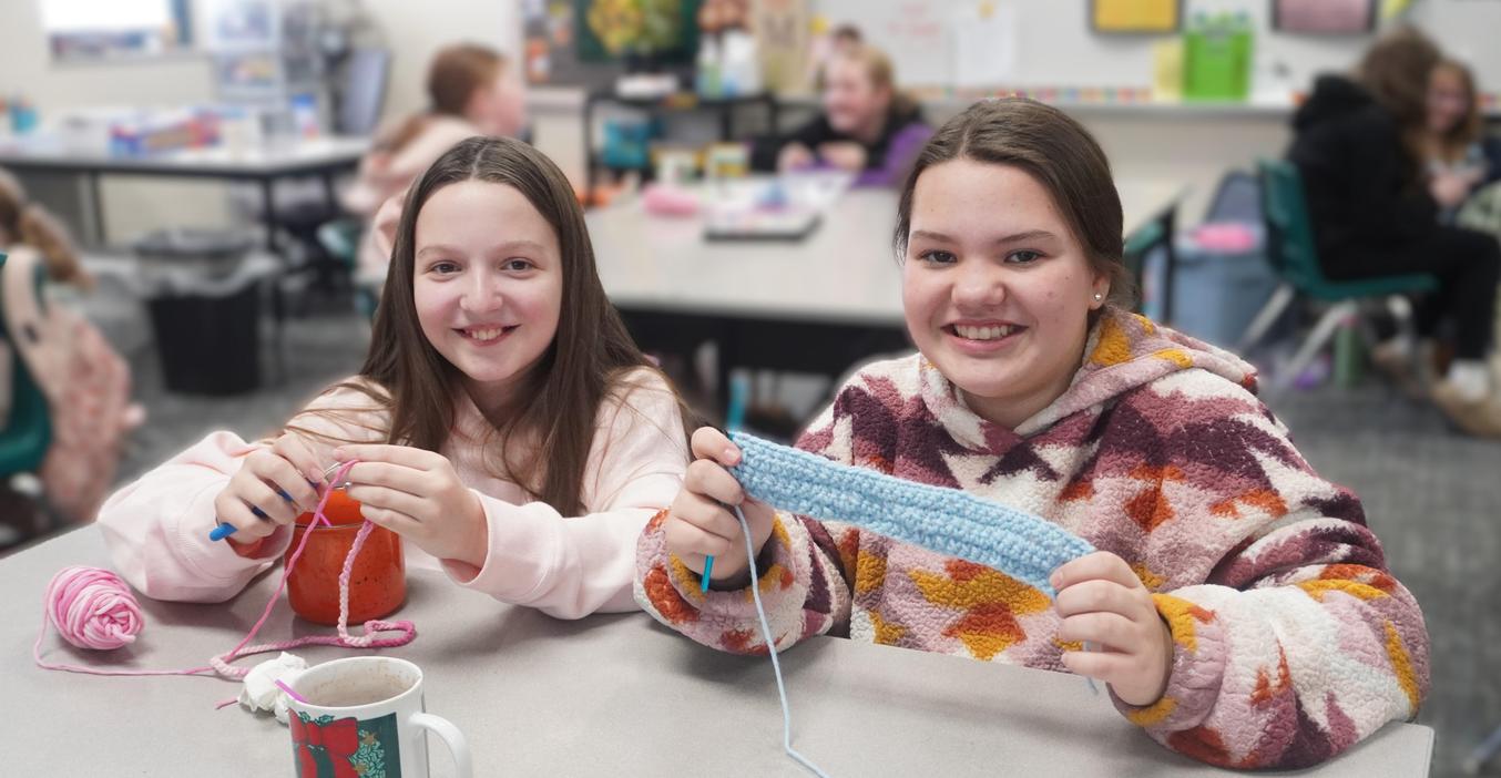 Two students enjoy working on a crochet project.