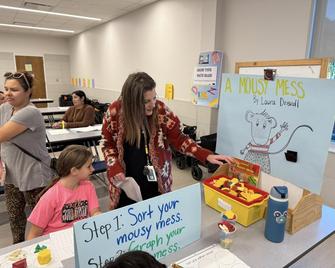 teacher looking at poster board with child at table
