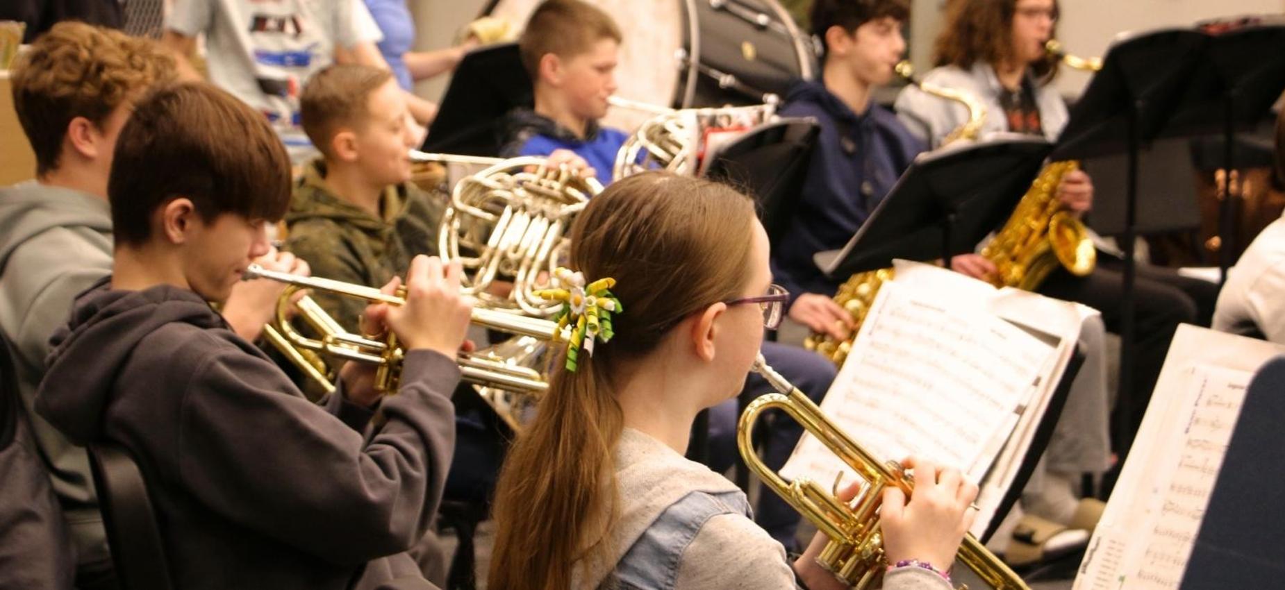 Students playing brass instruments in a band rehearsal setting.
