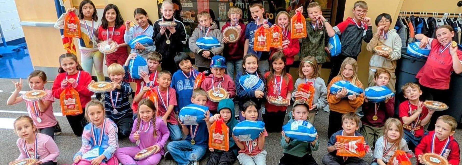 Group of children posing with medals and awards, celebrating achievements.
