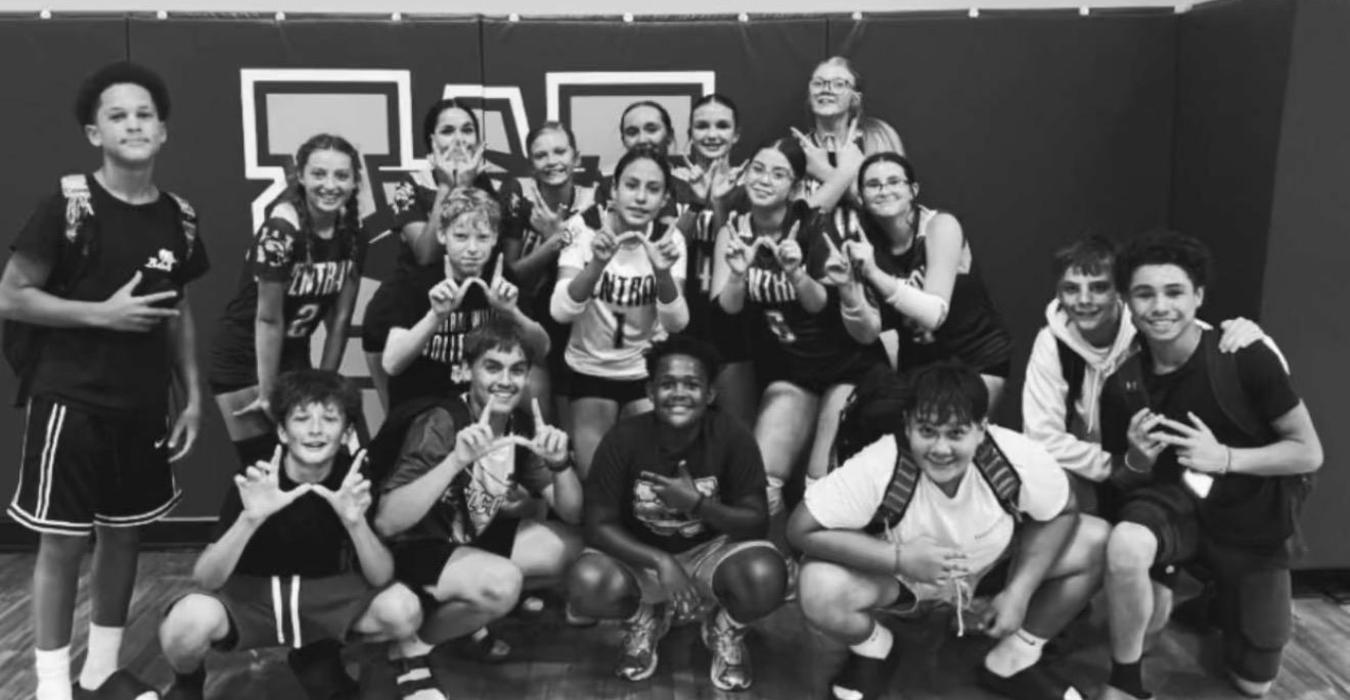 Group photo of a diverse team posing together in a gym.