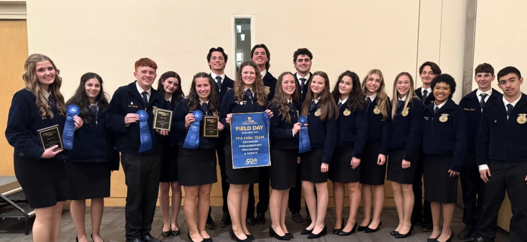 Group of students in formal attire holding awards and a sign for a field day event.