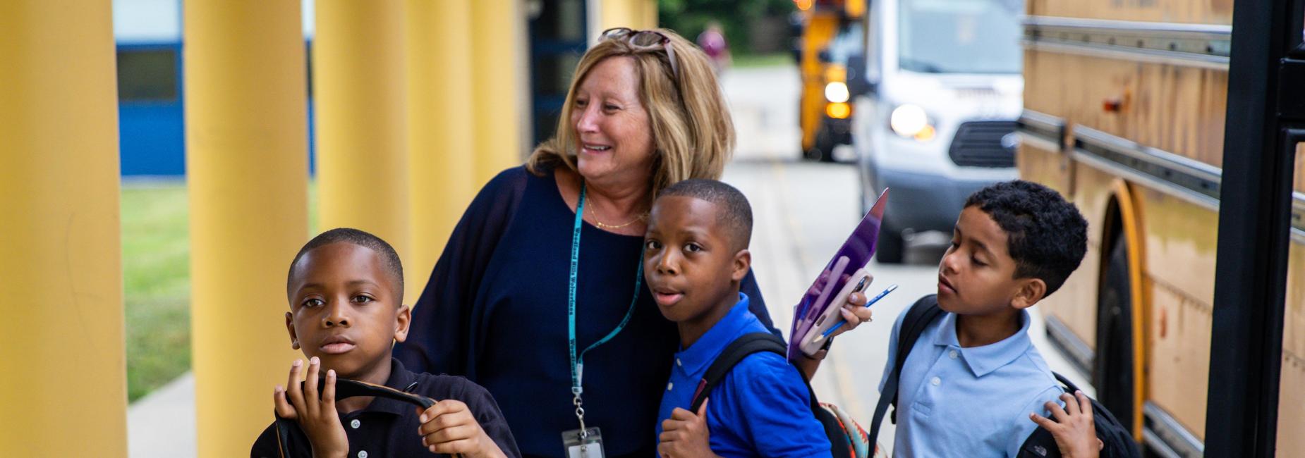 A teacher welcomes elementary students as they arrive to school