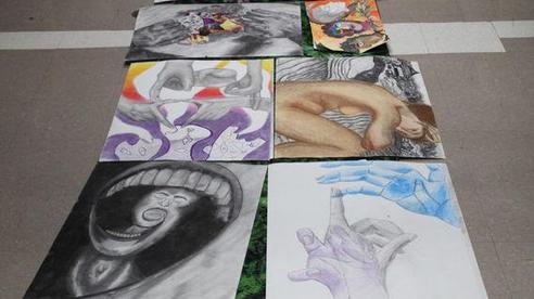 A collection of diverse artwork arranged on a floor, showcasing various styles and themes.
