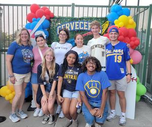 Group of people posing in front of a festive backdrop with balloons.
