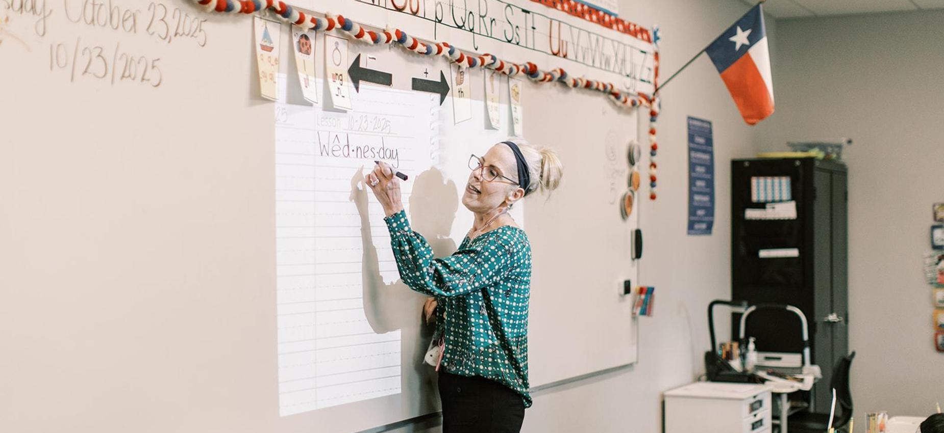 A teacher writes on the whiteboard in her classroom