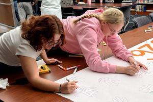 Two students write on a large piece of paper.