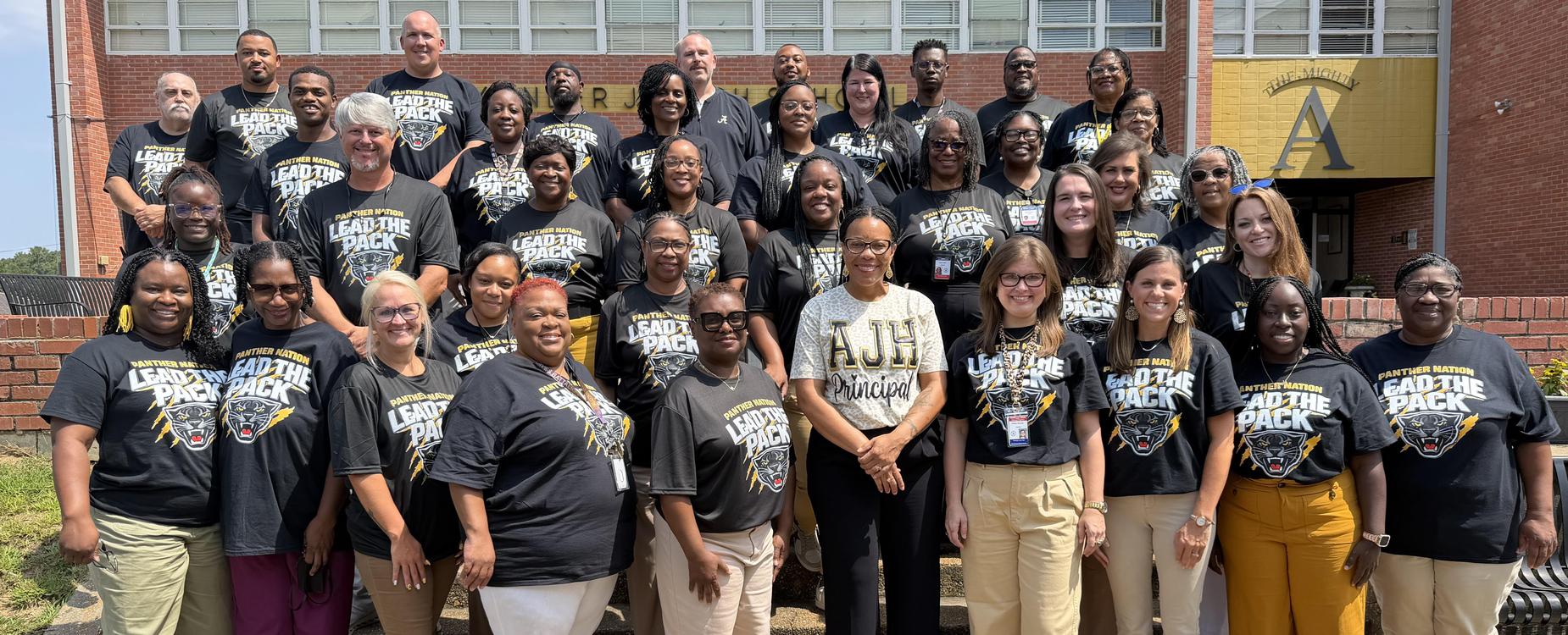 A large group of diverse people standing together, all wearing matching team shirts.