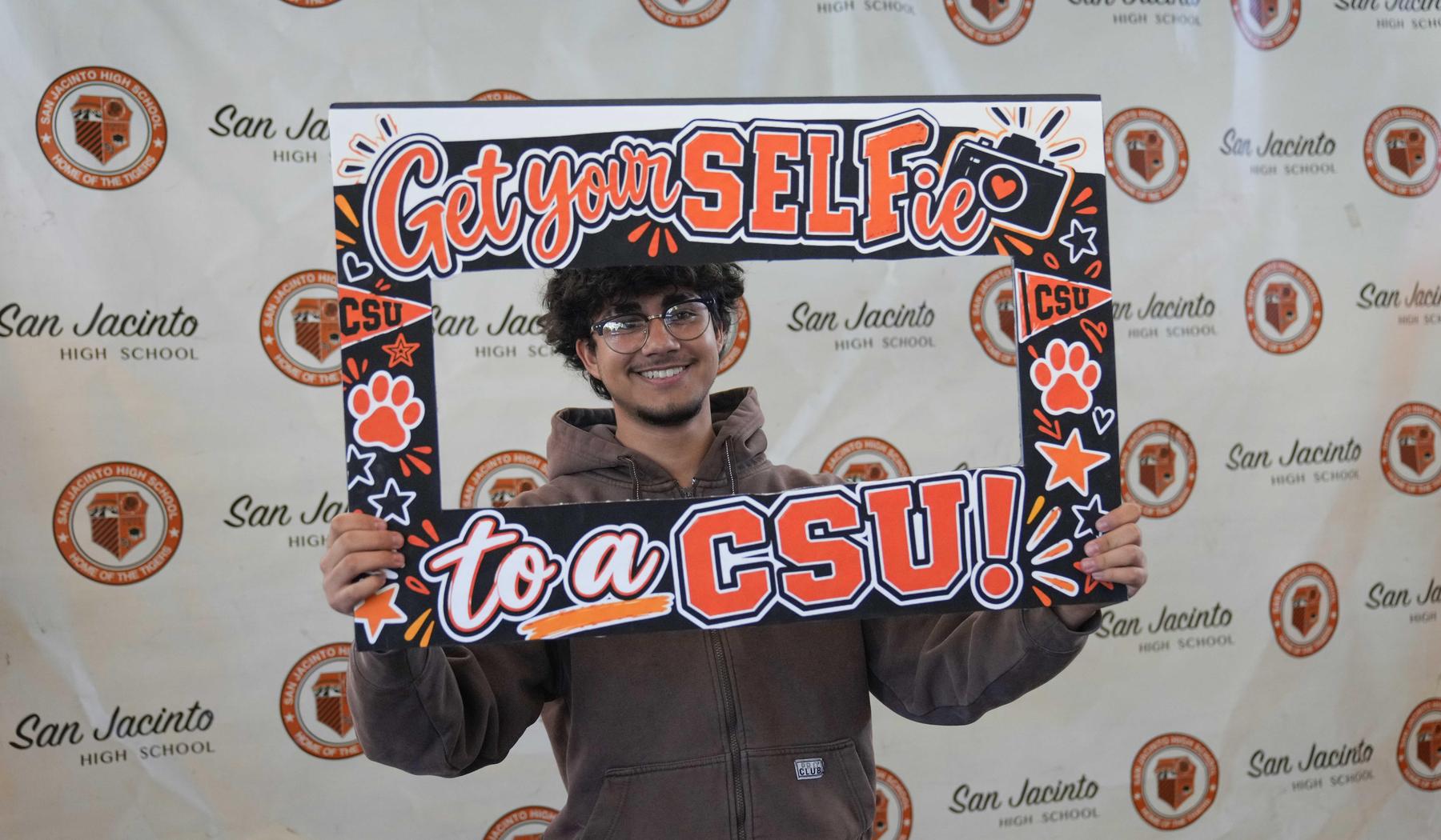 Boy holding a Get your SELFie to a CSU selfie frame.