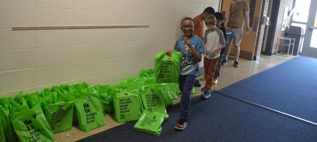 boy with big smile picks up a bag of books