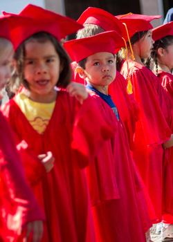 Elementary students wearing graduation gowns