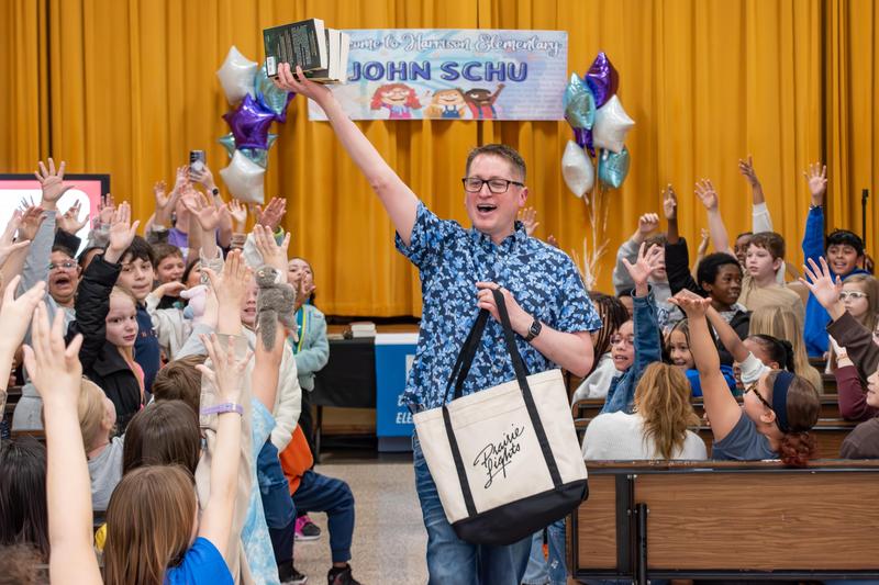 John Schu hands out free books during his assembly at Harrison Elementary to cheering students.