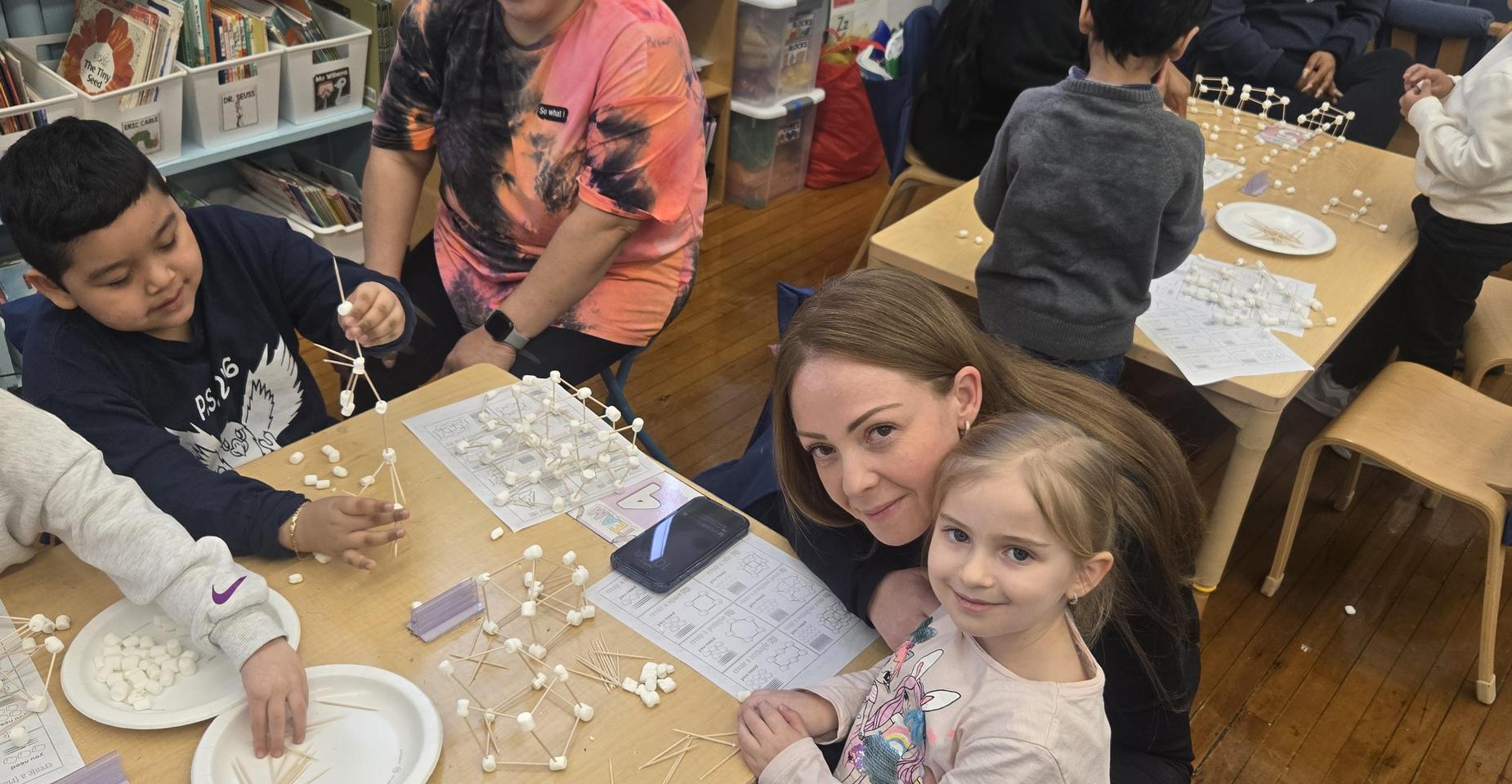 Students and adults engaged in a hands-on activity with marshmallows and toothpicks.