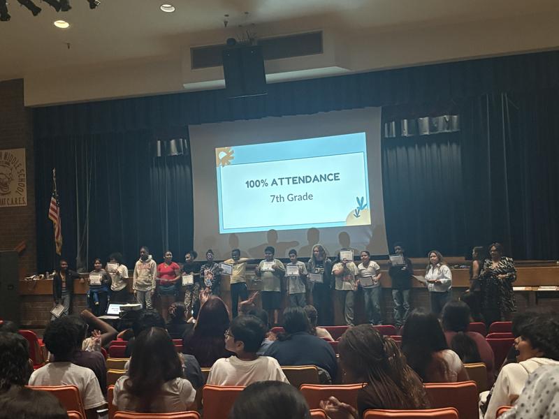 7th graders on stage holding 100% Attendance certificates