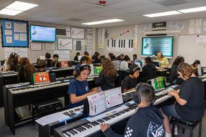 Students at Juliette Low School of the Arts practice piano in the school’s Piano Lab while wearing headphones and following music instruction.