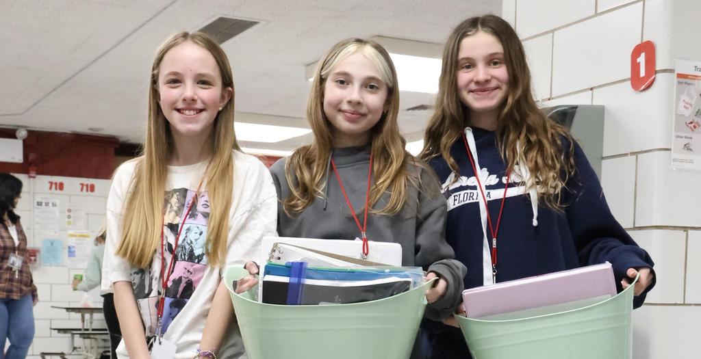 Three girls standing in the cafeteria.