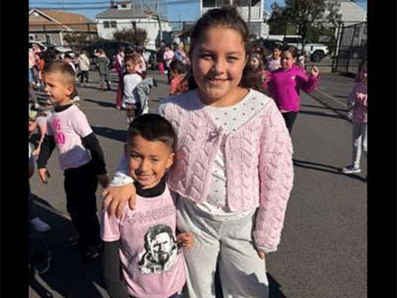 Students smiling outside in school parking lot.
