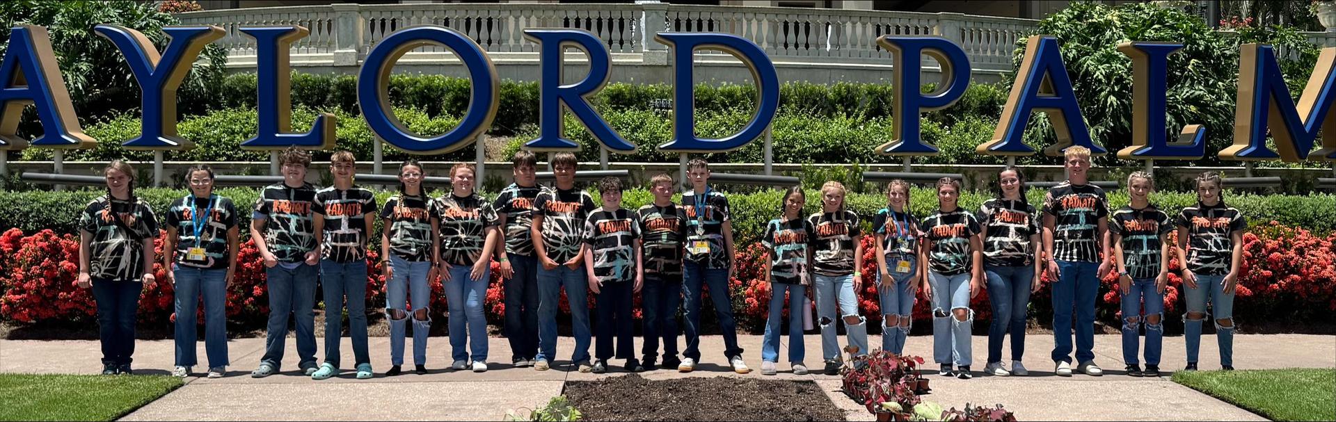 Group of students standing in front of flowers and plants having fun and laughing. 