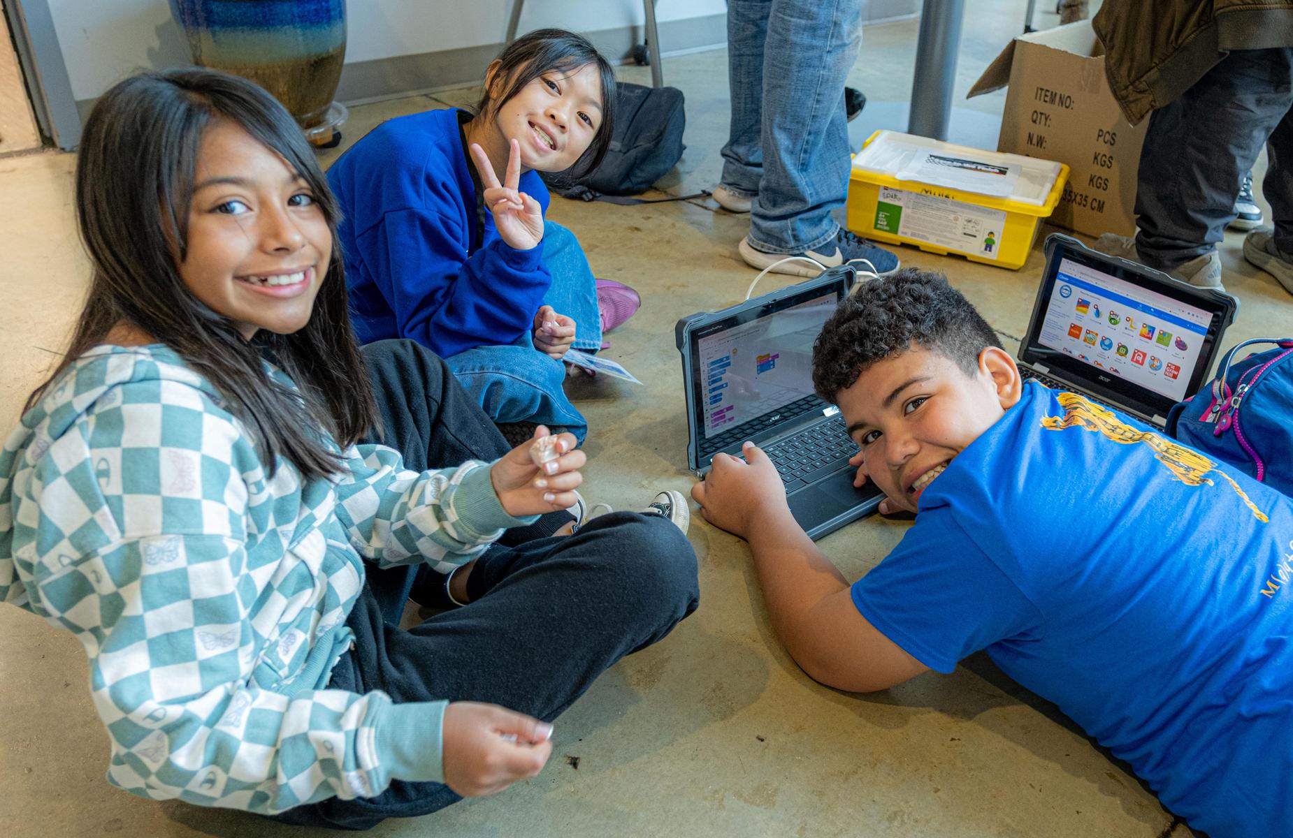 3 students code on the schools floor