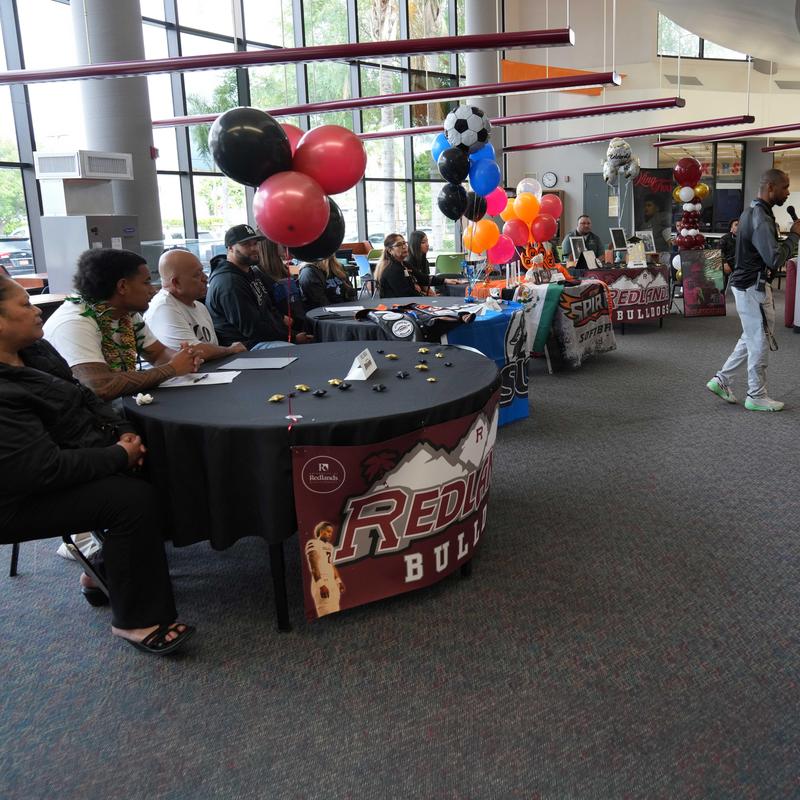 Athletes at tables in front of the room, waiting to sign commitment letters