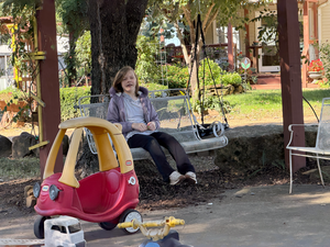 student swinging on bench in a wooded area
