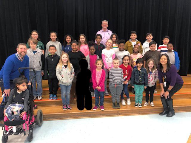 group of 26 students pose with 3 administrators on stage steps
