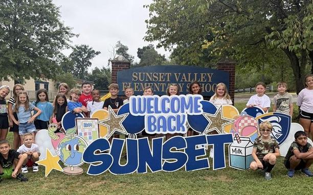 students with welcome back sign on the first day of school