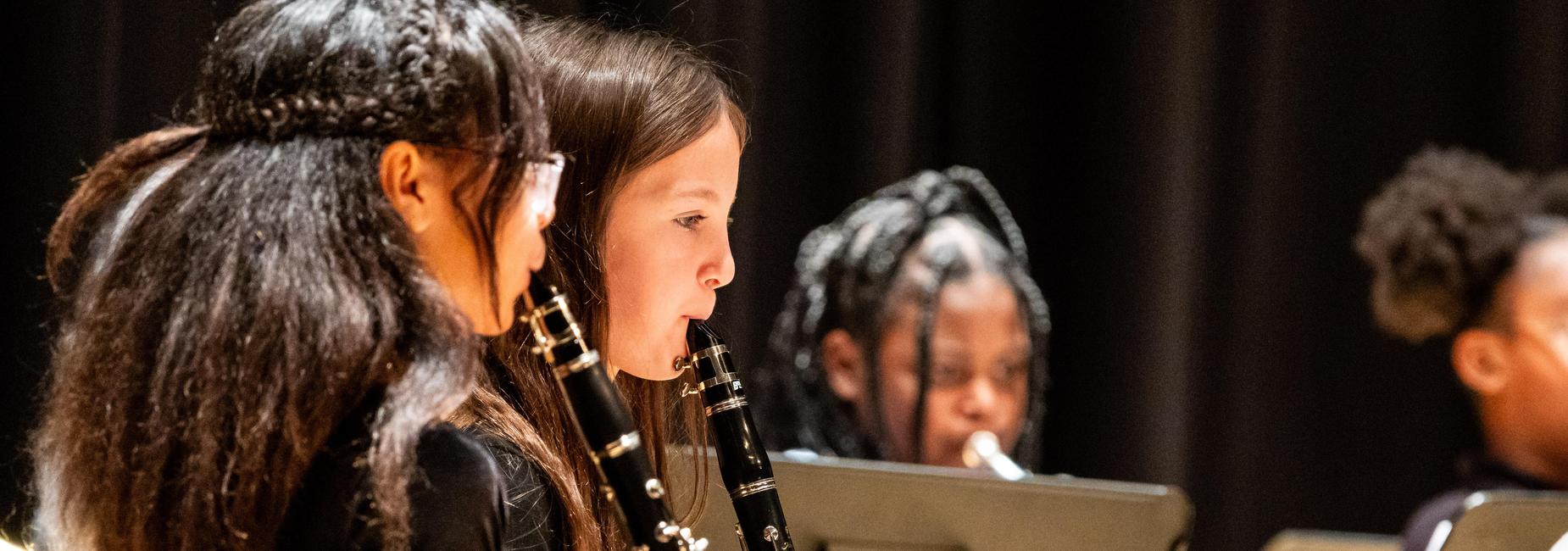 Elementary musicians perform their clarinets on stage