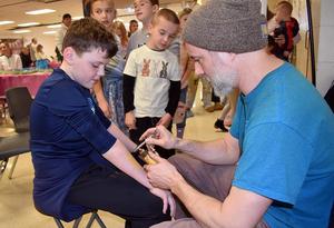 Boy receives a temporary tattoo while a group of children watches.