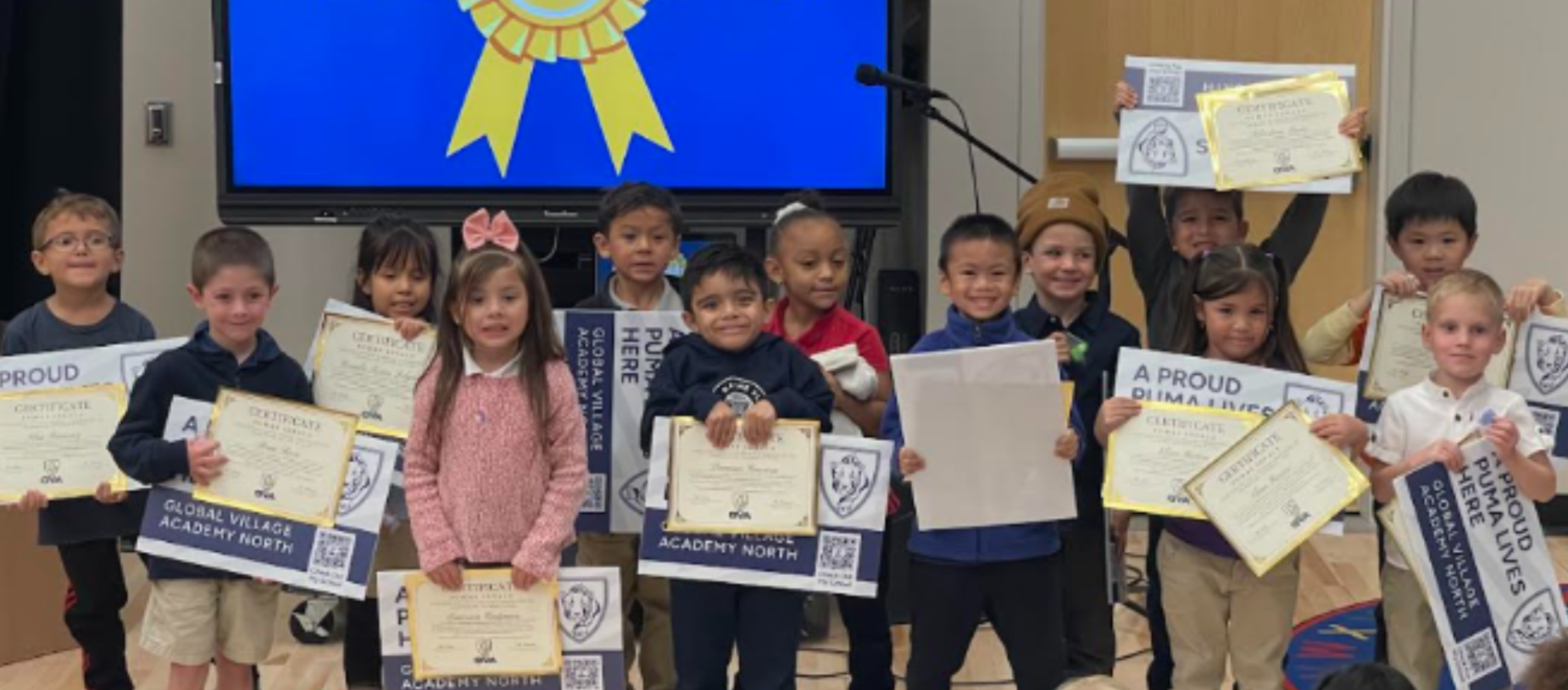 A group of children holding various awards and certificates in a school setting.
