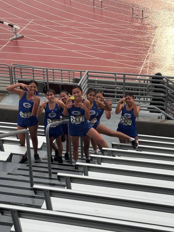 abut 7 students pose in group photo at track meet during rain