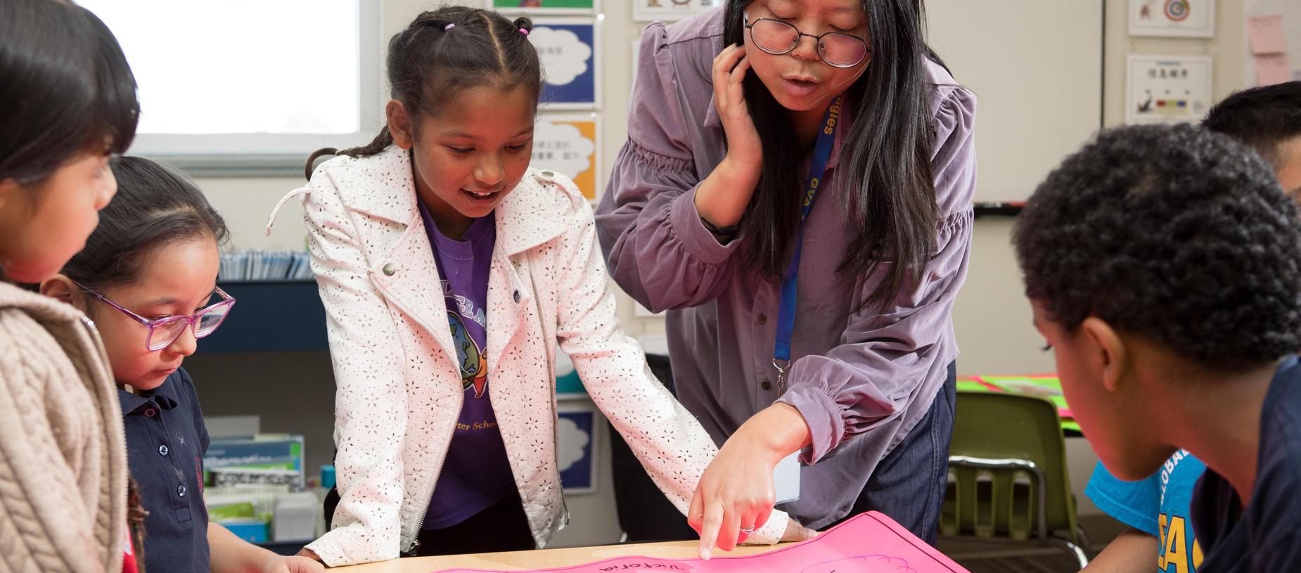 A teacher guiding students through a hands-on activity in a classroom.