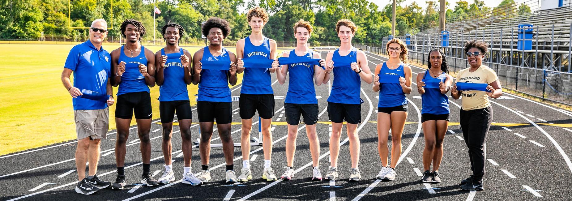 Group of track athletes posing together on a running track.