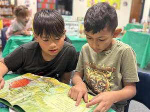 two elementary boys reading book together