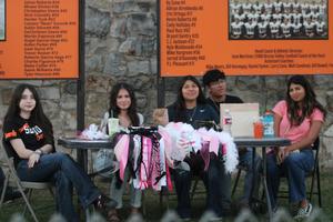 Group of five people sitting at a table with cheerleading materials and drinks.