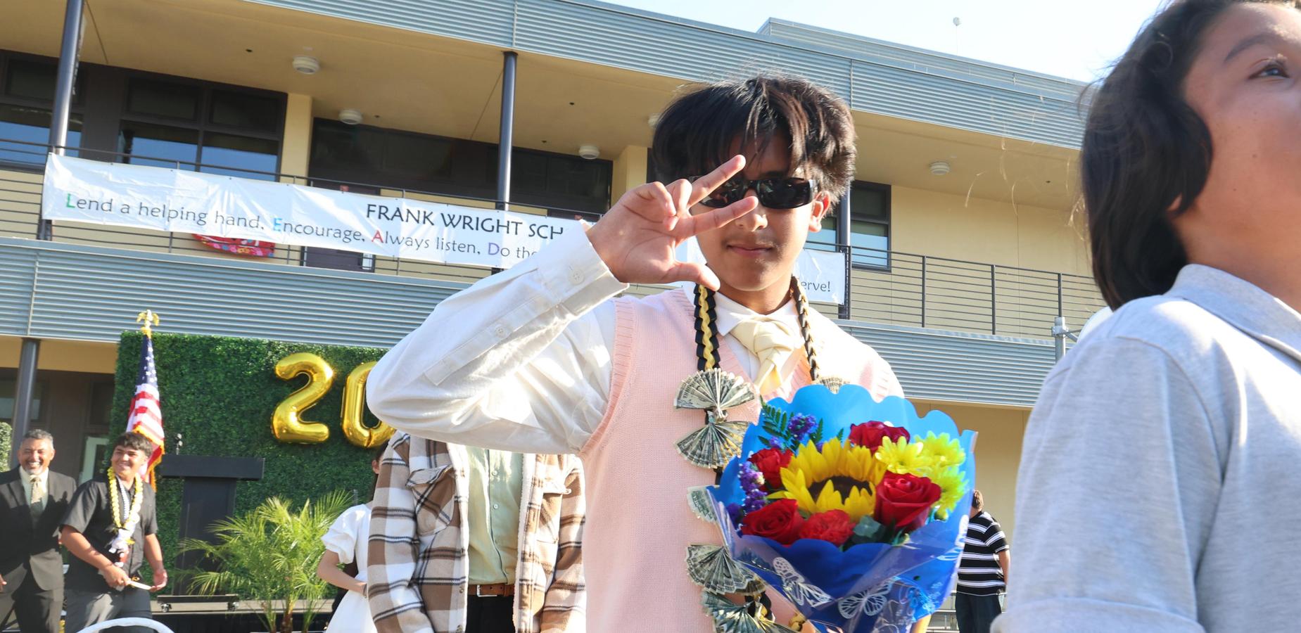 A student holds a bouquet and smiles during a school event.