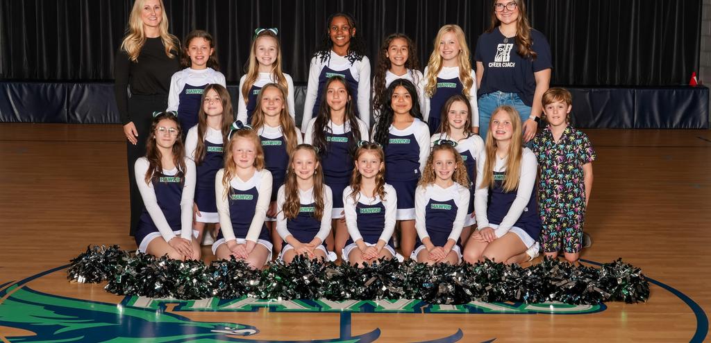Cheerleading squad posed together on a gym floor with pom-poms and smiles.