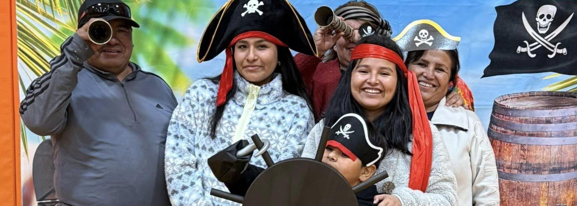 A child in a pirate hat interacting with a steering wheel surrounded by family.