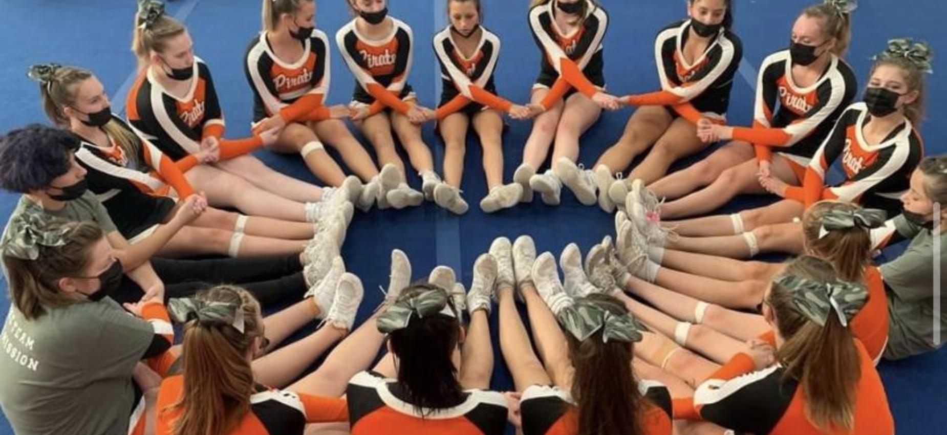 OHS Cheerleaders seated in a circle with hands crossed.