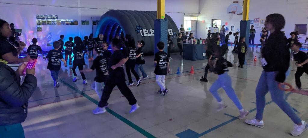 dozens of student running a track lit with neon lights