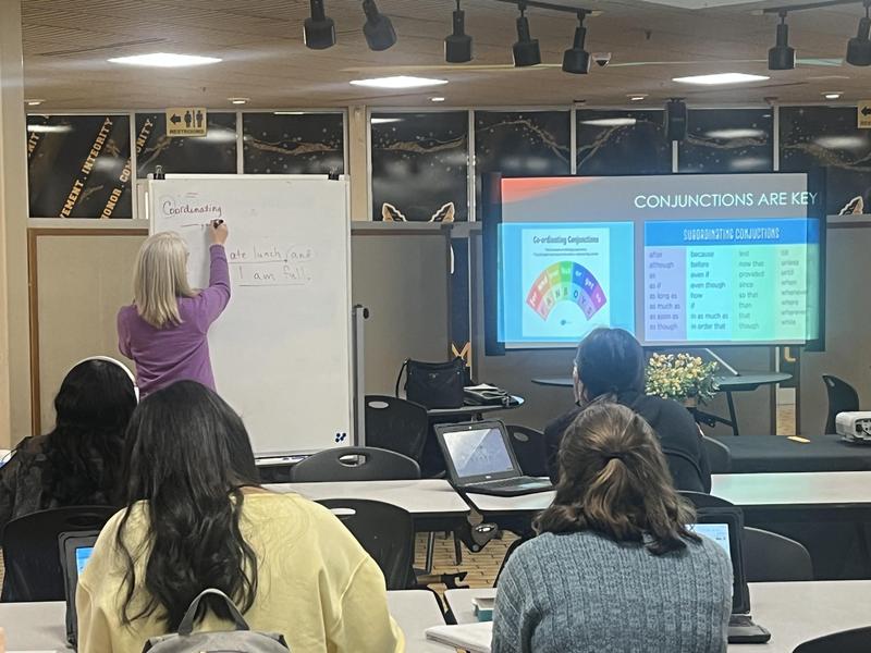 English and Reading instructor writes on white board in front of the juniors