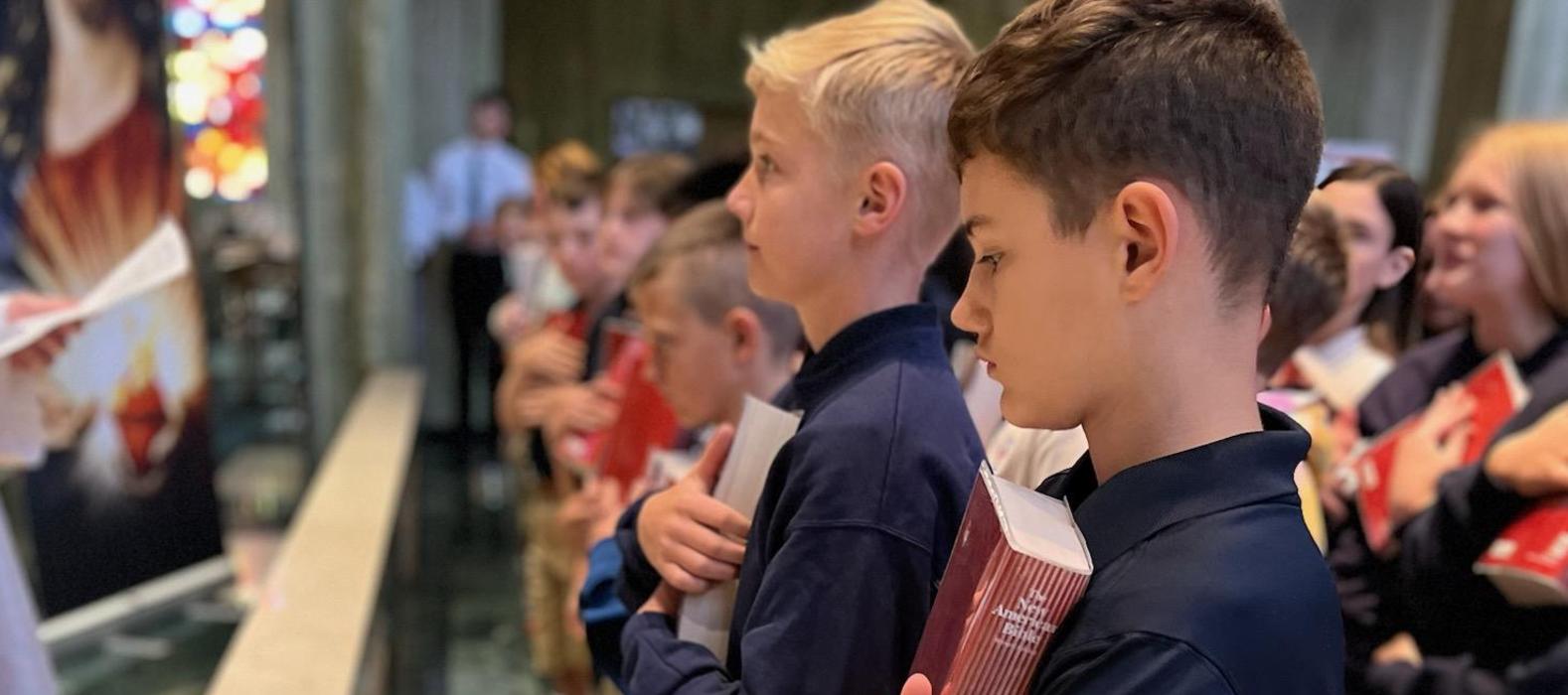 Students holding books and standing in a religious setting.