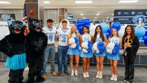 A group of cheerleaders, the student emcees, mascots, and Principal Campbell