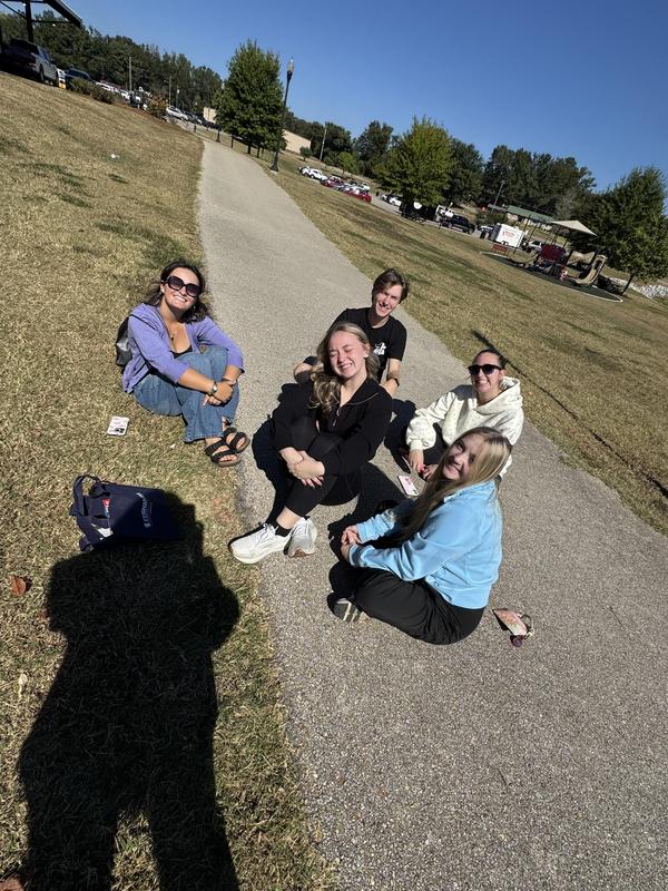 students resting their legs, sitting on the sidewalk