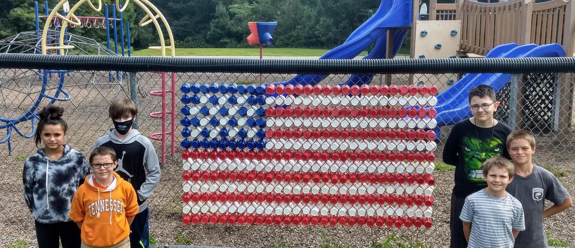 students made an american flag out of plastic cups on the playground fence