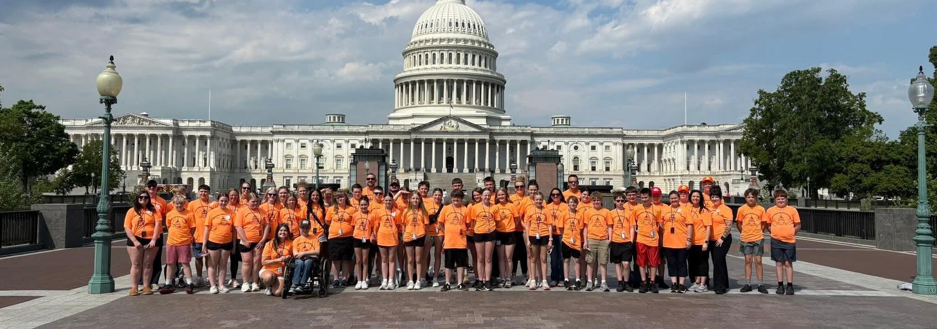 middle school students and adults standing in multiple rows in front of building in Washington, DC during a field trip