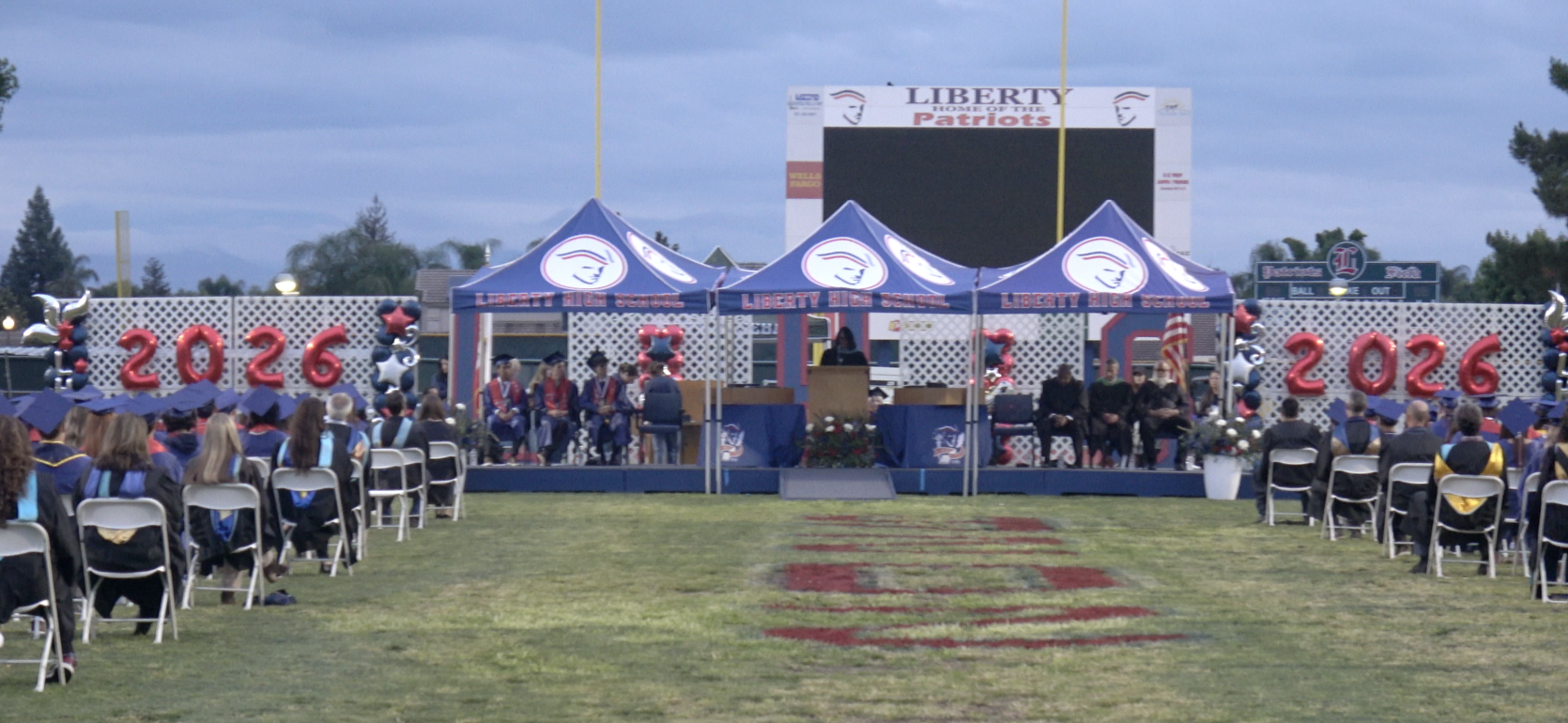 Graduation ceremony at Liberty Patriots with stage and audience in attendance.