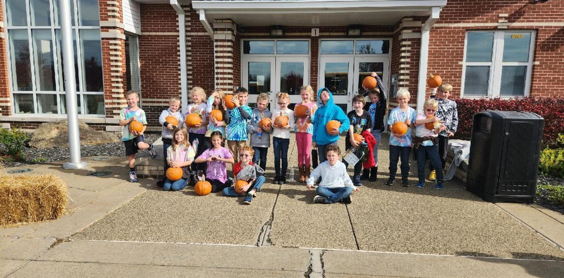 students outside school with pumpkins