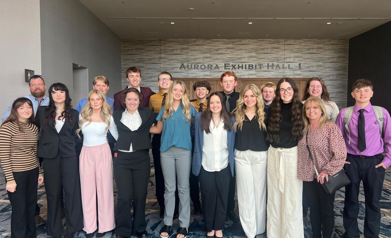 A large group of students in formal attire posing together in a hall.