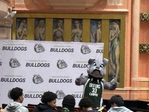 Bulldog mascot posing with students in front of a backdrop at the event.